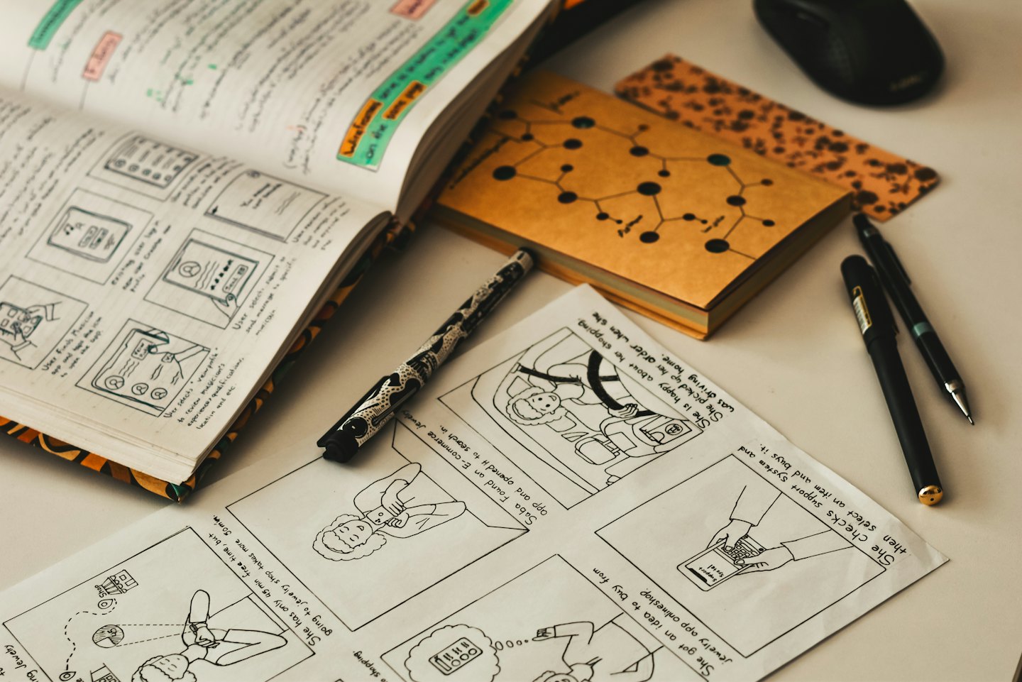 UX design sketches and flowcharts spread across a wooden desk.
