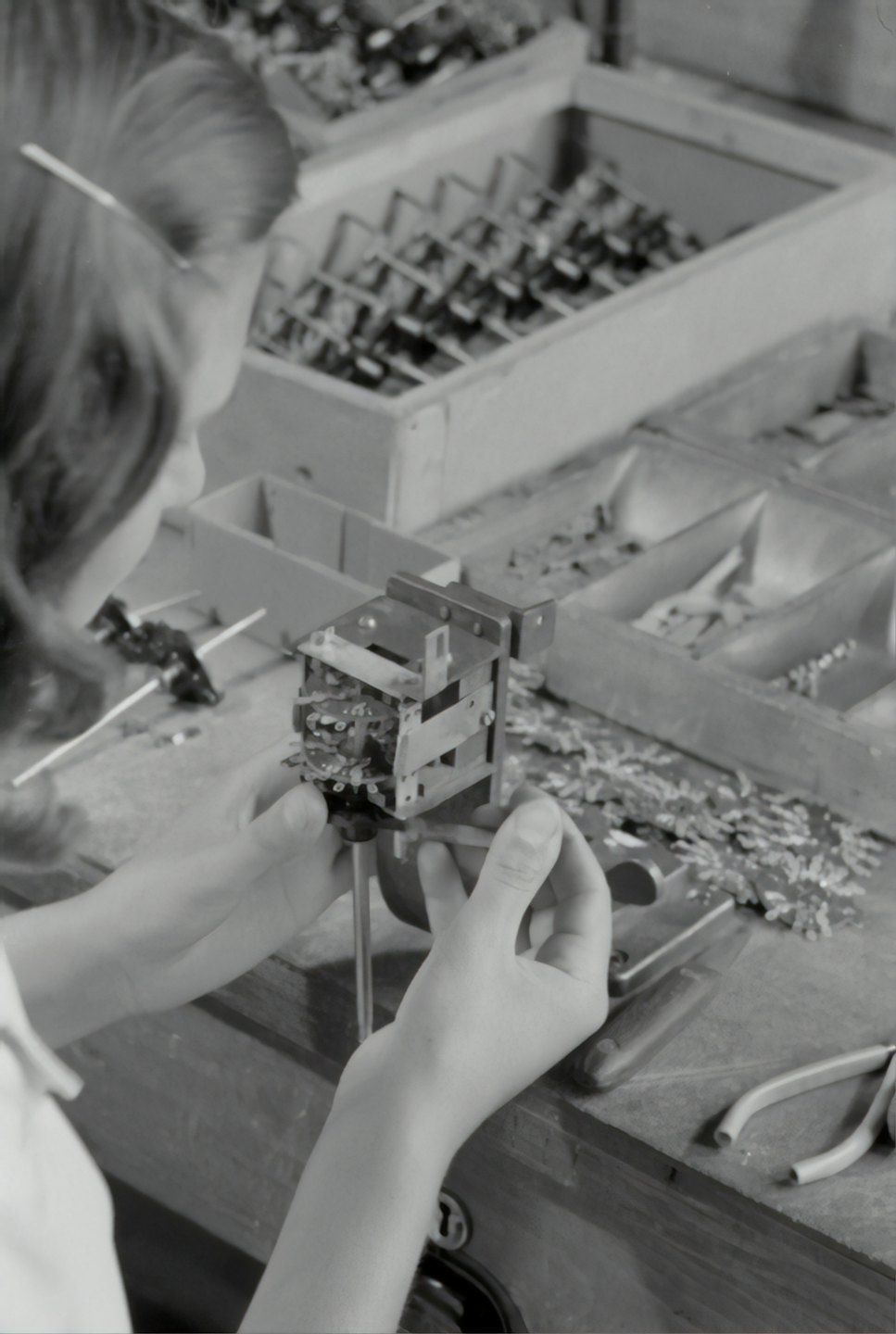 Hands assembling a small metal component with a tool.